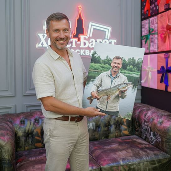 Мужчина держит картину в с фотографией рыбака